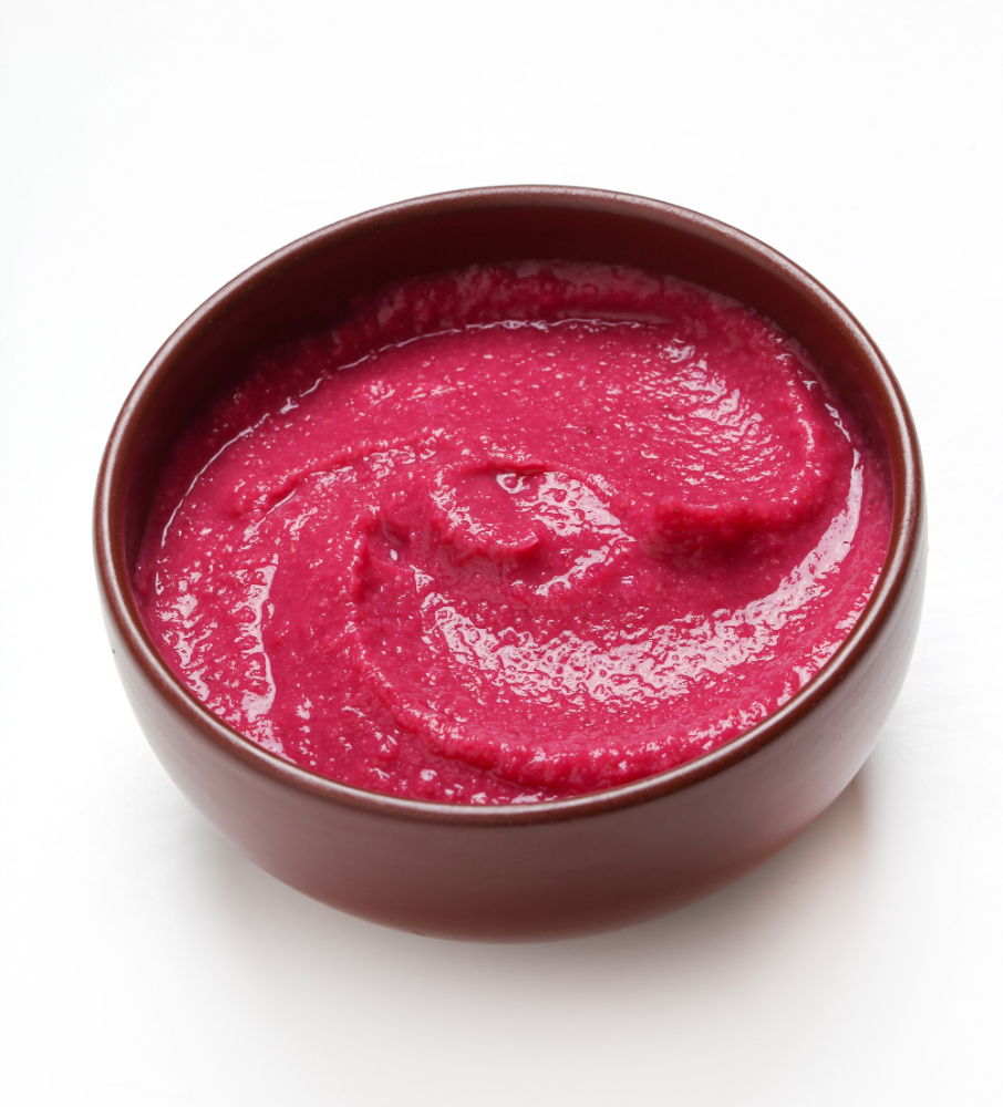 A smooth and vibrant red strawberry puree in a small bowl, The puree has a thick, velvety texture, showcasing its rich, natural color.