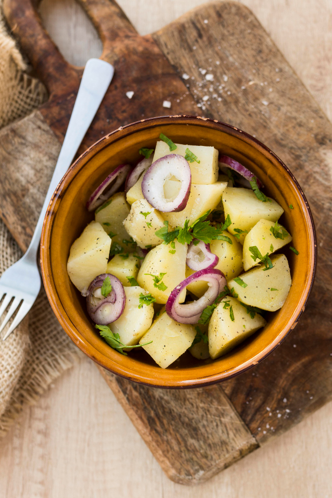 "Close-up view of a vibrant potato salad served in a bowl, featuring diced potatoes, chopped herbs, and creamy dressing, garnished with fresh parsley for a delicious and refreshing look."