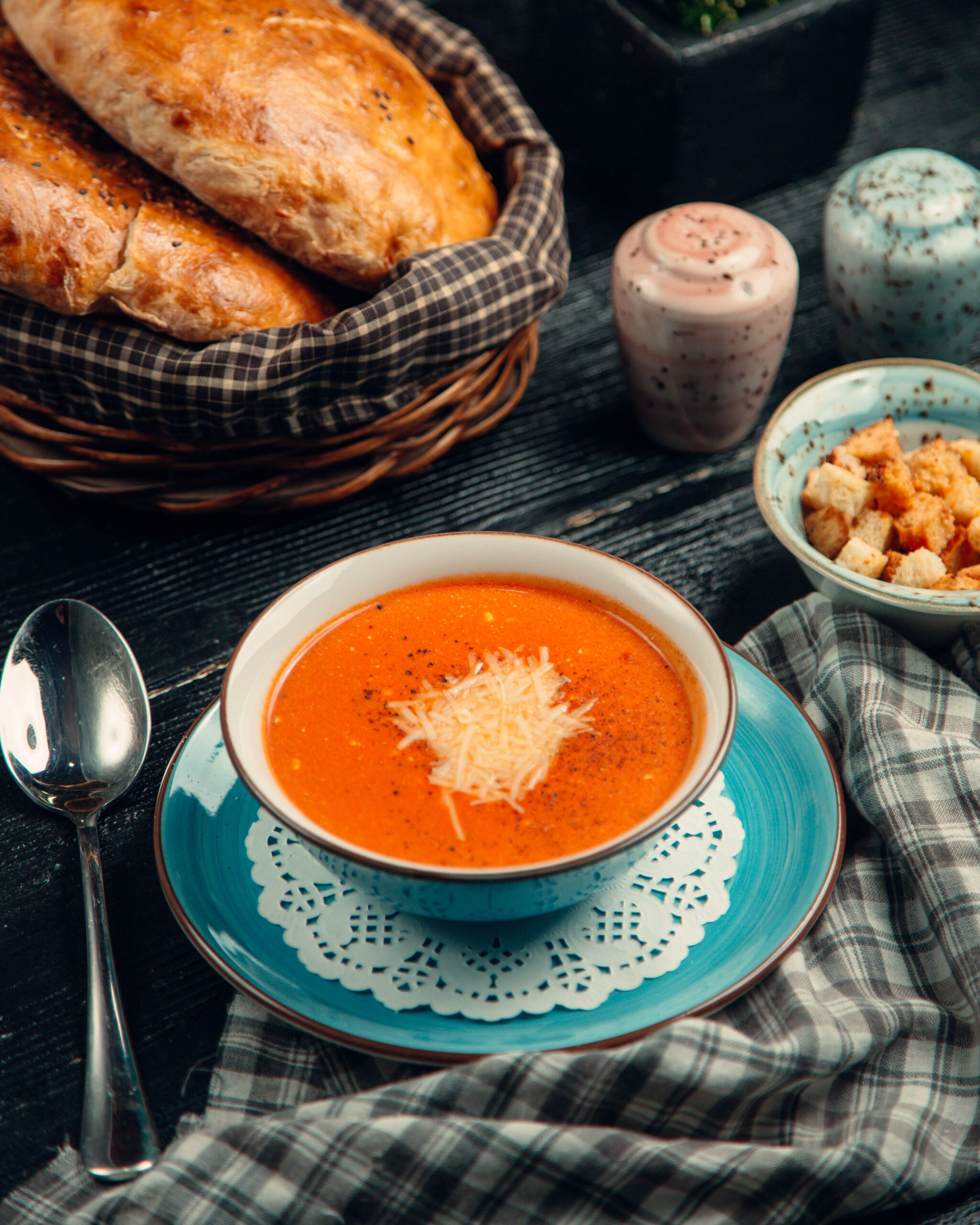 A plate of grilled cheese sandwiches with a steaming bowl of tomato soup.